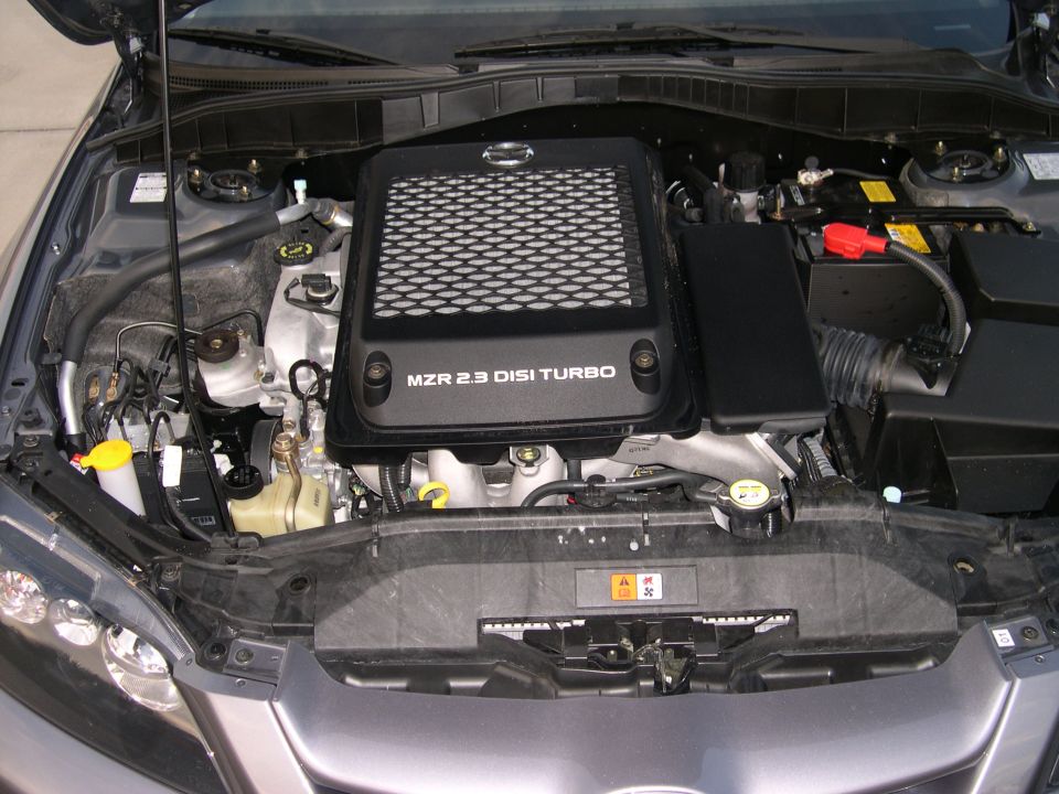 Engine bay with "MZR 2.3 DISI TURBO" cover, gray exterior paint, and visible headlights