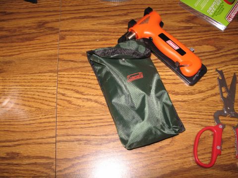 1995 Ford Bronco - Coleman camping stove, pouch, and multi-tool are laid out on a wooden table surface.