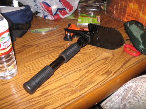 1995 Ford Bronco - A folding shovel is placed on a wooden table, with various items in the background.