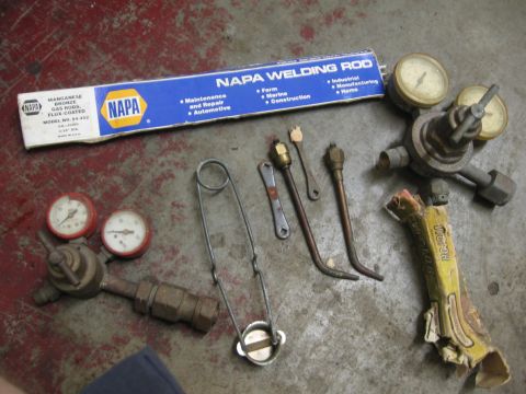 1974 Ford F-100 - Assorted welding supplies including NAPA rods, a gas regulator, and torch components are laid out.