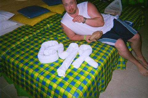 1984 Ford Bronco - Man relaxes on a bed adorned with towel art and a distinctive checkered comforter.