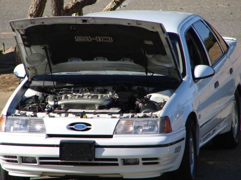 1992 Ford Taurus - This white 1992 Ford Taurus SHO sedan is shown from the front with its hood open, revealing the engine compartment.