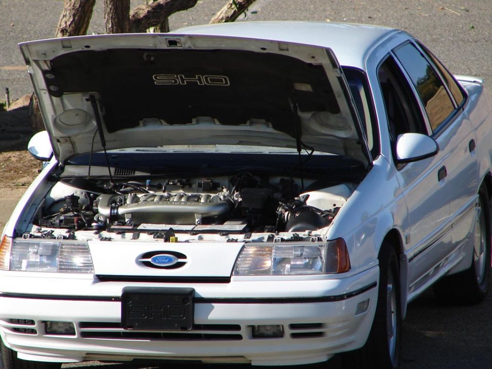 White 1992 Ford Taurus SHO sedan with hood open, showing engine. Front view