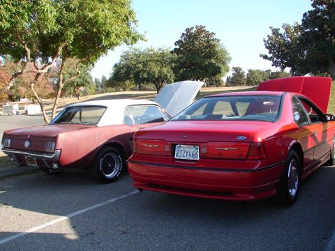1992 Ford Taurus - A red 1992 Ford Thunderbird is parked next to a classic car, both with hoods open.