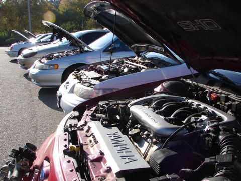 1992 Ford Taurus - Multiple cars lined up with hoods open, showing their engines at an event.