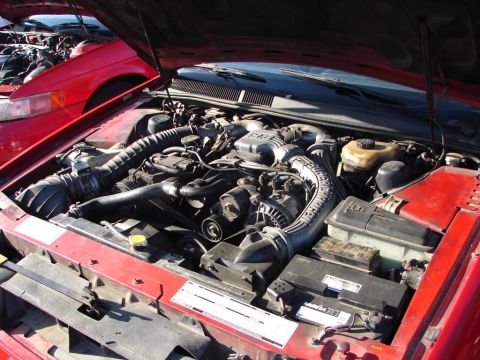 1992 Ford Taurus - The engine bay of a red 1992 Ford Taurus is visible, with another red vehicle partially seen in the background.