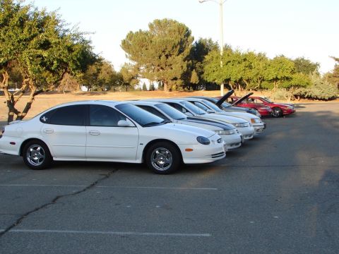 1992 Ford Taurus - A line of cars, including a white 1996 Ford Taurus, are parked in an outdoor lot.