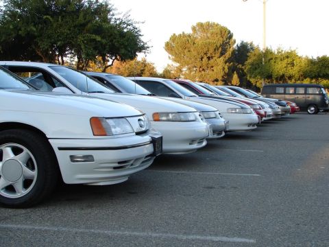 1992 Ford Taurus - Multiple white 1992 Ford Taurus sedans are parked in a lot, with a dark van visible in the distance.