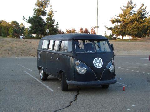 1992 Ford Taurus - A dark-colored Volkswagen Type 2 van is parked in a lot, showing its iconic front emblem and rounded headlights.