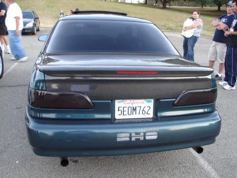 1992 Ford Taurus - A teal sedan is parked outdoors with people in the background. The car has custom taillights and a spoiler.