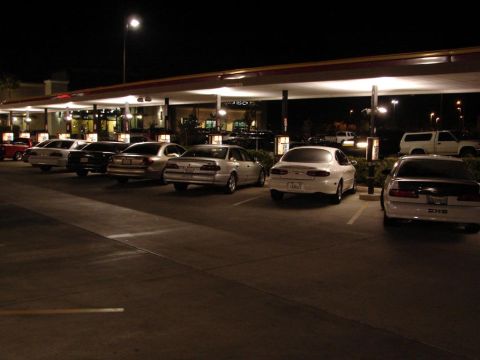 1992 Ford Taurus - A white 1992 Ford Taurus is parked in a lot at night, with other vehicles visible.