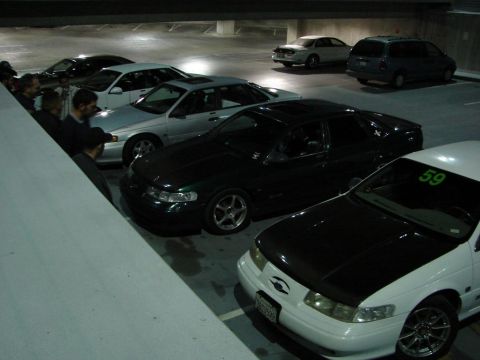 1992 Ford Taurus - A dark green 1992 Ford Taurus is parked in a garage alongside other vehicles.