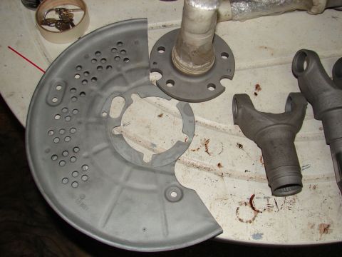 1996 Ford Bronco - Various automotive parts, including a dust shield and driveshaft yokes, laid out on a table.