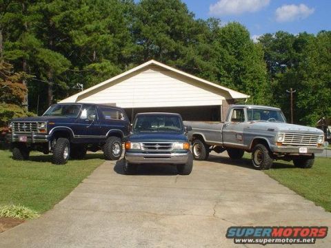 1968 Ford Mustang - Three trucks and a blue Bronco are parked in a driveway in front of a garage on a sunny day.