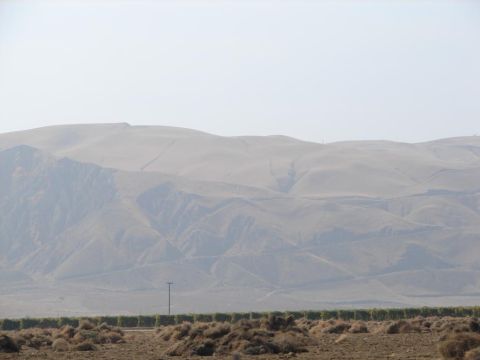 1992 Ford Taurus - A hazy, dusty landscape with rolling hills and dry vegetation in the foreground. A single utility pole stands tall against the muted sky.