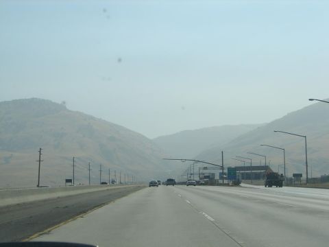 1992 Ford Taurus - A wide highway stretches towards distant mountains under a hazy sky, with multiple vehicles in motion.