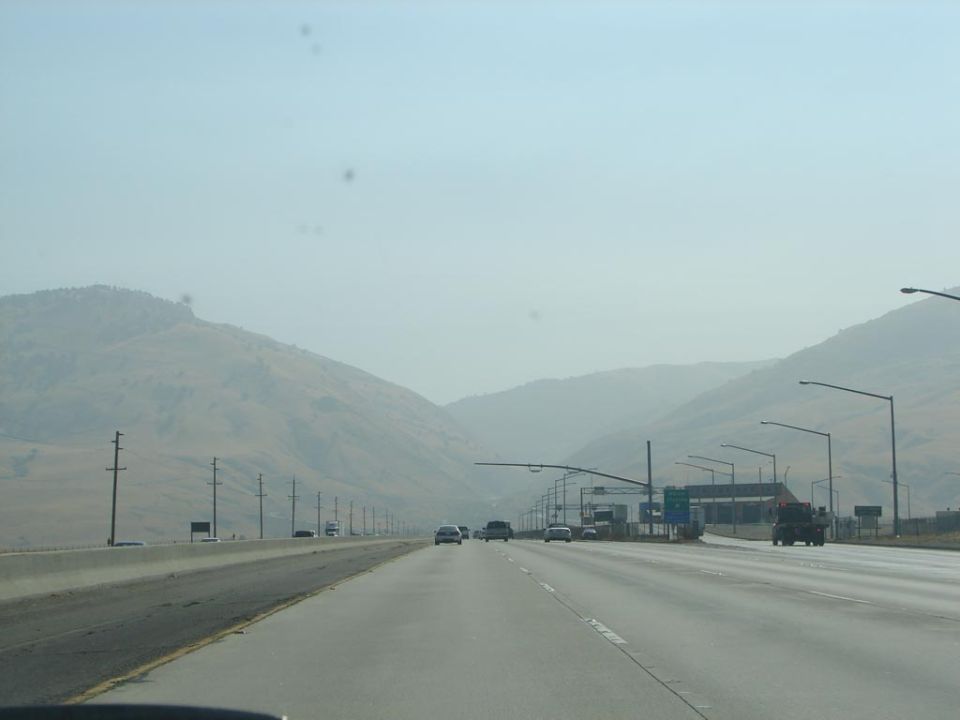 Highway with mountains in the background and several cars driving on a sunny day