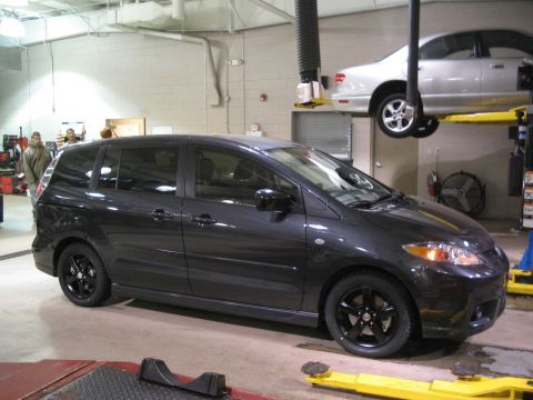 2006 Mazda Mazda 5 - Dark gray 2006 Mazda Mazda 5 is shown on a car lift in a service bay, with another vehicle overhead.