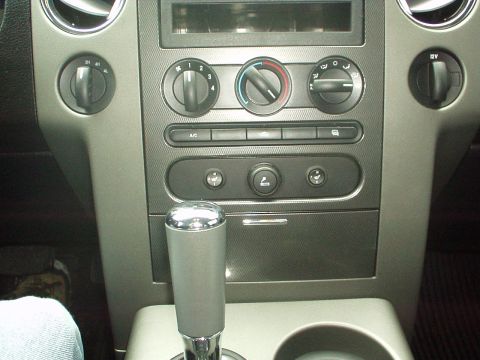 1994 Ford Bronco - The interior of a vehicle shows the center console with climate controls and a gear shifter.