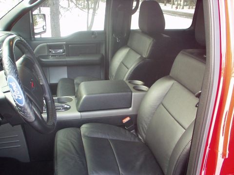 1994 Ford Bronco - The interior of a red Ford F-150 features black leather seats and a center console with cup holders.