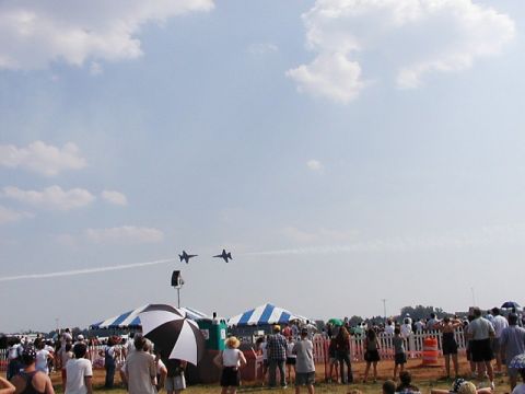 1998 Ford Taurus - An airshow features two fighter jets performing maneuvers for a crowd gathered below.