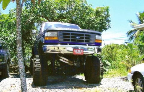 1974 Ford F-100 - This lifted Ford pickup truck has a distinctive purple paint job and a prominent black grille with the Ford logo.