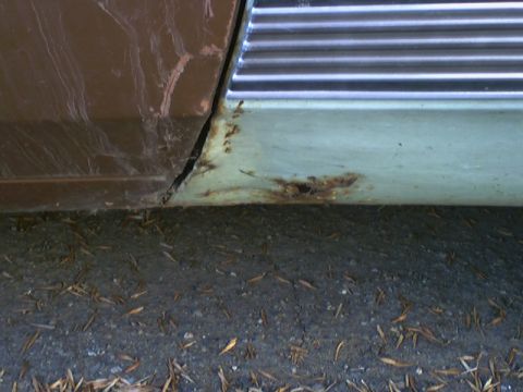 1973 Ford Ranchero - Rust is visible on the lower part of a car door, next to horizontal chrome trim.