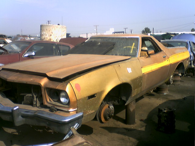 Gold and brown 1973 Ford Ranchero with yellow stripe, missing wheels