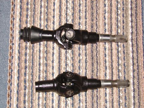 1996 Ford Bronco - Two driveshafts with universal joints are shown on a carpeted surface.