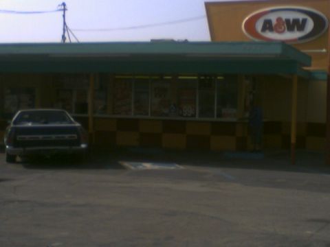 1973 Ford Ranchero - A dark sedan is parked in front of an A&W restaurant with a checkerboard pattern on the lower wall.