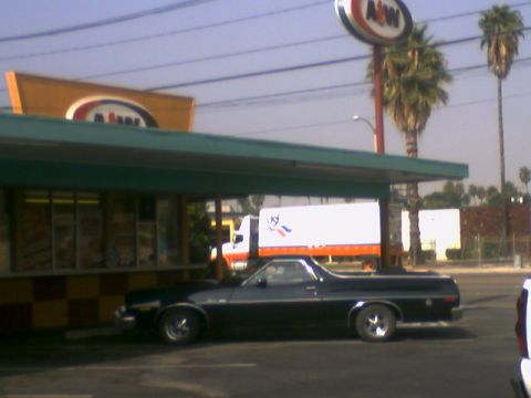 1973 Ford Ranchero - A black Ford Ranchero is parked next to a building with an A&W sign.