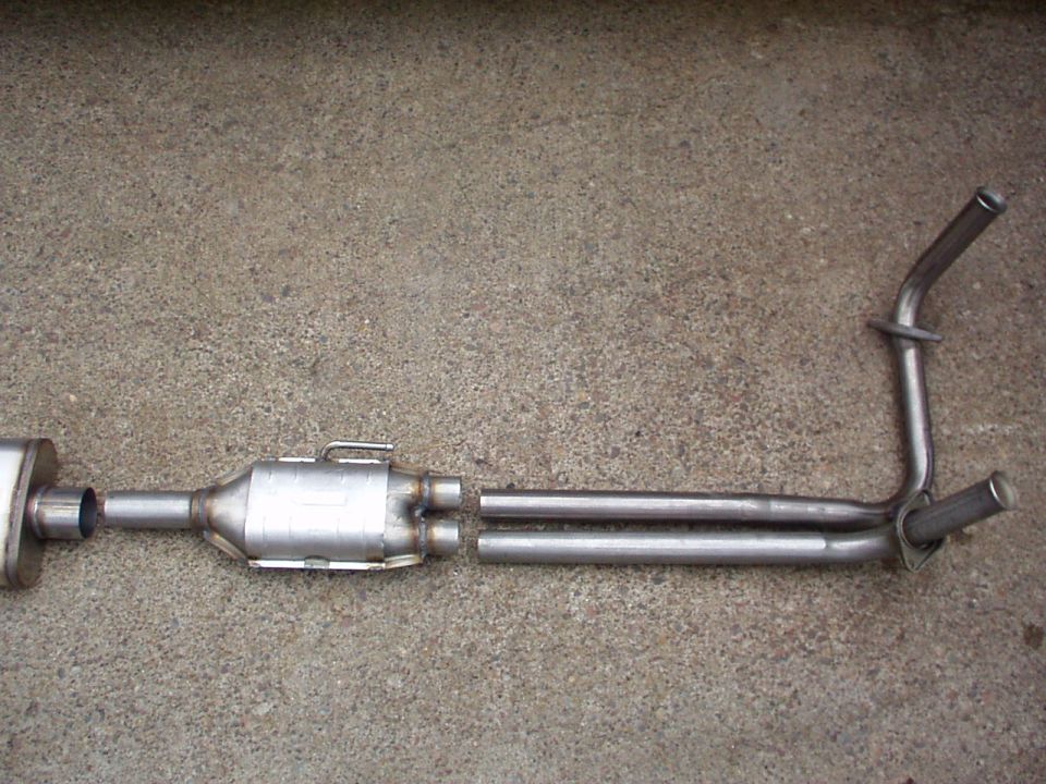 Exhaust system part with catalytic converter and dual pipes on concrete