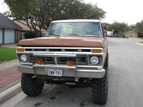 1979 Ford Bronco - This lifted Ford truck is parked on a residential street with a 'For Sale' sign displayed on its windshield.