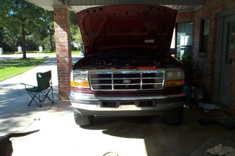 1996 Ford Bronco - This Ford F-Series truck, likely from the late 1990s, is parked in a driveway with its hood up.