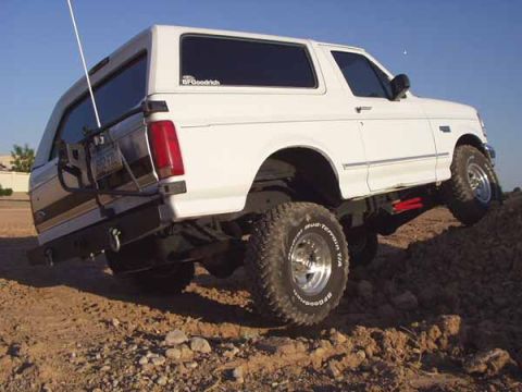 1993 Ford Bronco - This SUV is equipped with large off-road tires and is navigating a dirt incline.