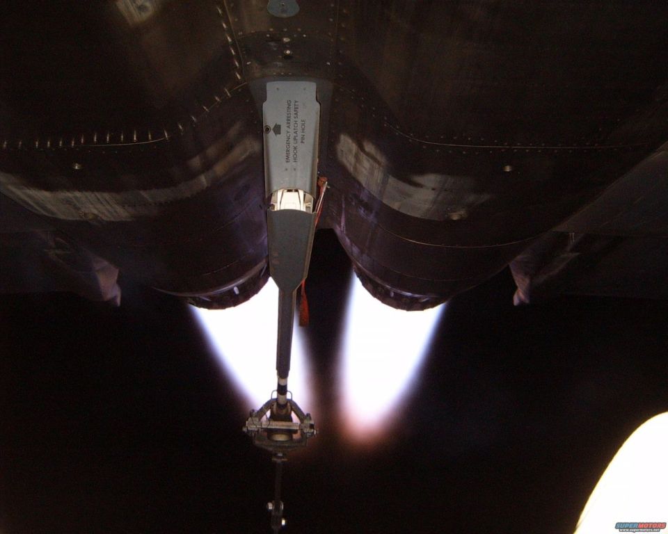 Underside of a fighter jet in afterburner with arresting hook lowered