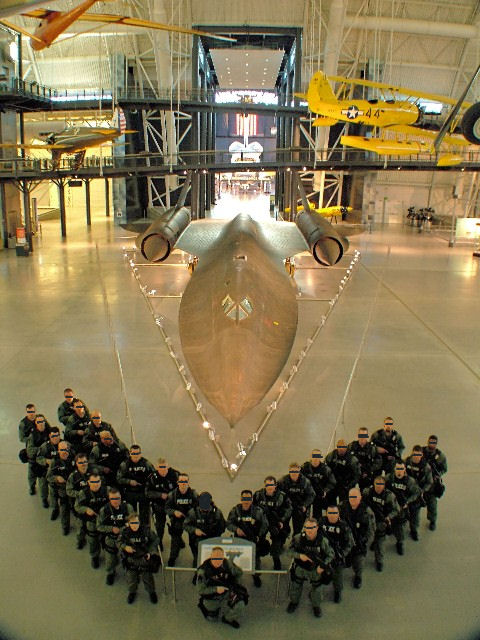 2001 Ford Crown Victoria - A group of people in tactical gear stand in front of a Blackbird aircraft inside a museum.