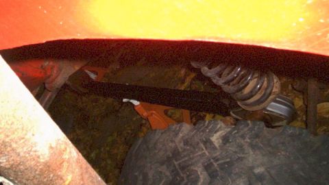 1978 Ford Bronco - Close-up view of suspension components and a tire on an orange vehicle, with a watermark from Supermotors.net visible.