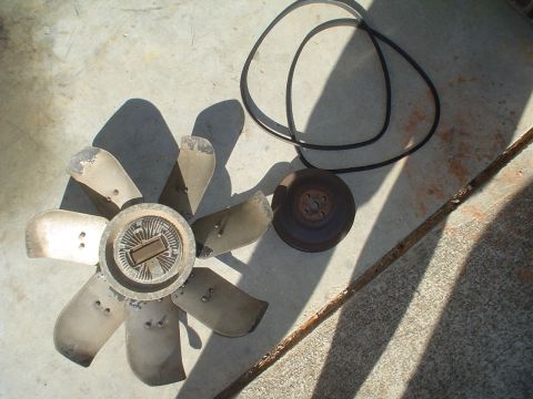 1967 Ford F-250 - Engine parts including a fan, belt, and pulley are laid out on a concrete surface.