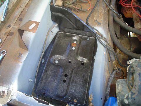 1967 Ford F-250 - Close-up of a black battery tray installed in the engine bay, surrounded by various hoses and wiring.