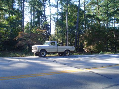 1967 Ford F-250 - A classic 1967 Ford F-250 pickup truck is parked on the shoulder of a two-lane road.