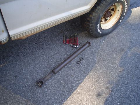 1967 Ford F-250 - A removed driveshaft and a set of wrenches lie on the ground next to a white truck.