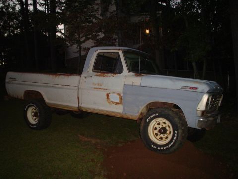 1967 Ford F-250 - This vintage Ford pickup truck shows signs of wear and tear, with a primer gray fender contrasting the weathered white body.