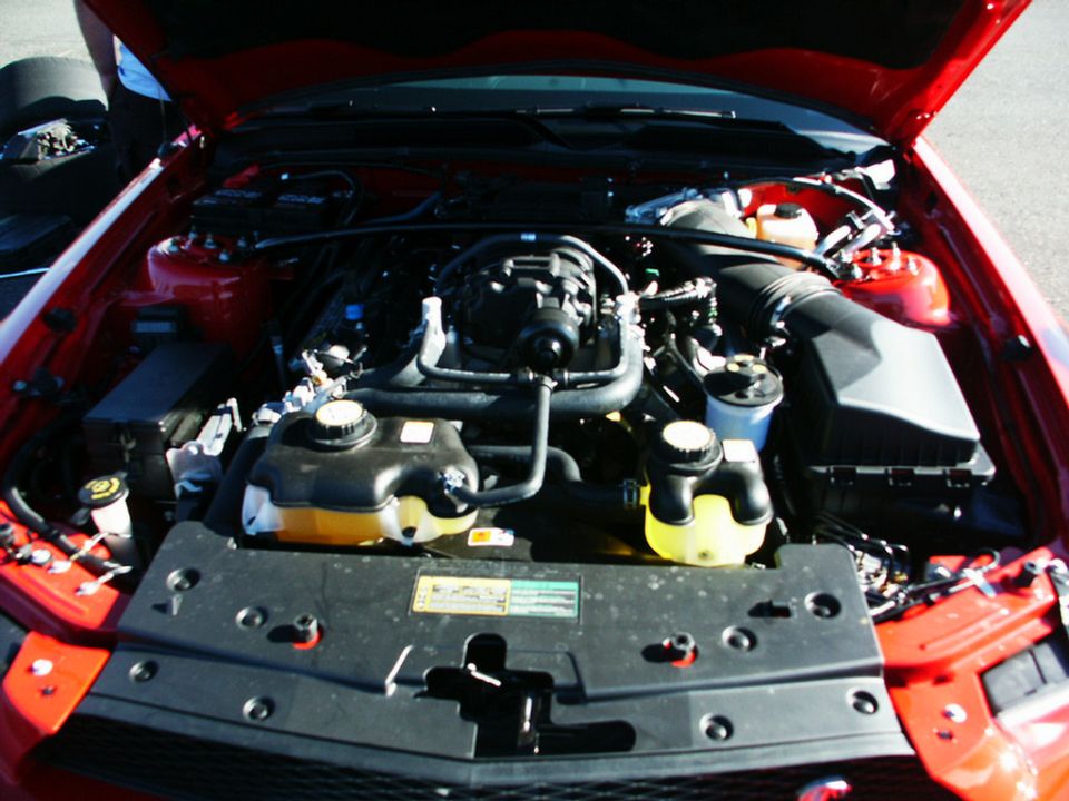 Red engine bay with black hoses and yellow fluid reservoirs. Supermotors.net logo visible