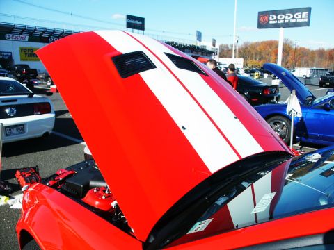 2001 Mercury Grand Marquis - A red car with racing stripes has its hood open at an outdoor event with other vehicles present.