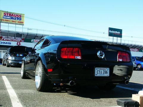 2001 Mercury Grand Marquis - Rear view of a black Ford Mustang with louvers and custom wheels parked at a track event.
