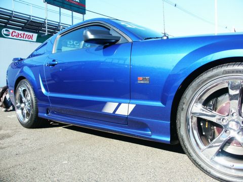 2001 Mercury Grand Marquis - A blue Ford Mustang coupe is shown from the side with racing stripes and chrome wheels.