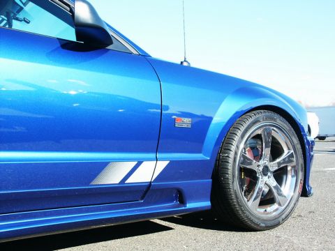 2001 Mercury Grand Marquis - A blue car with racing stripes and chrome wheels is seen from the side.