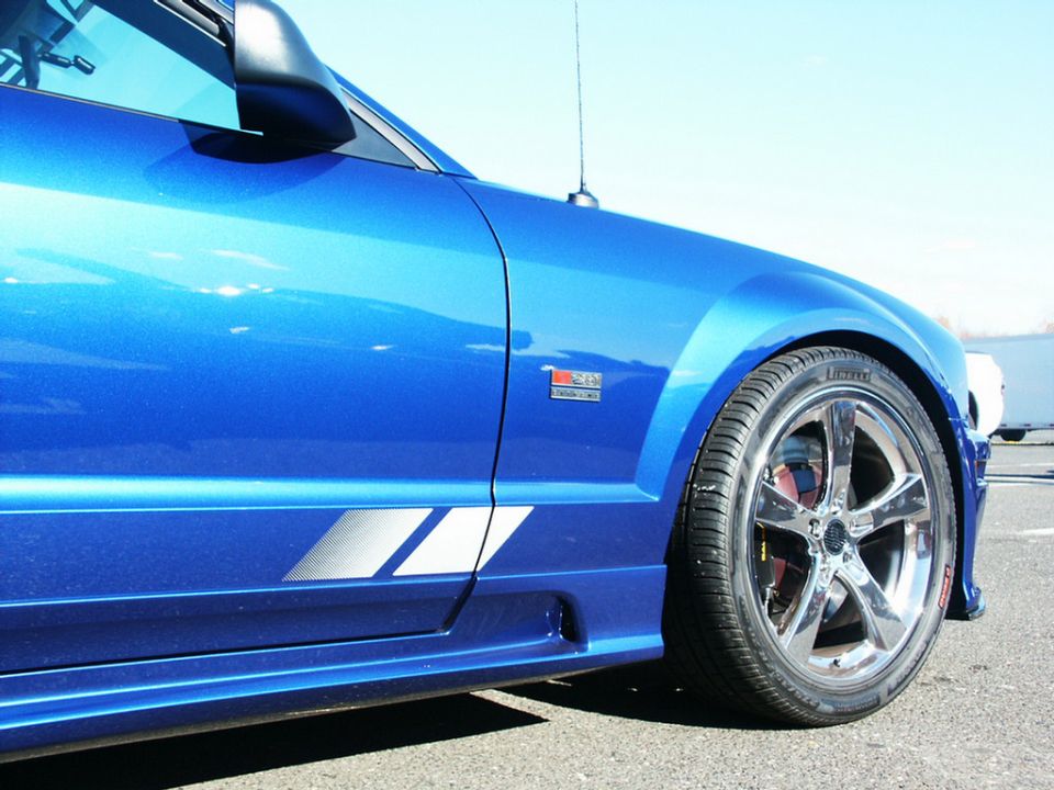 Blue car side view with racing stripes and chrome wheels