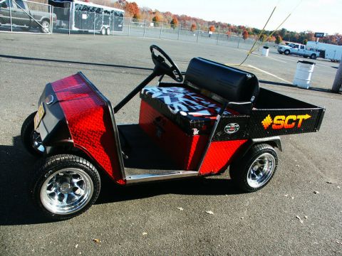 2001 Mercury Grand Marquis - A customized golf cart with a utility bed is parked in an asphalt lot on a sunny day.